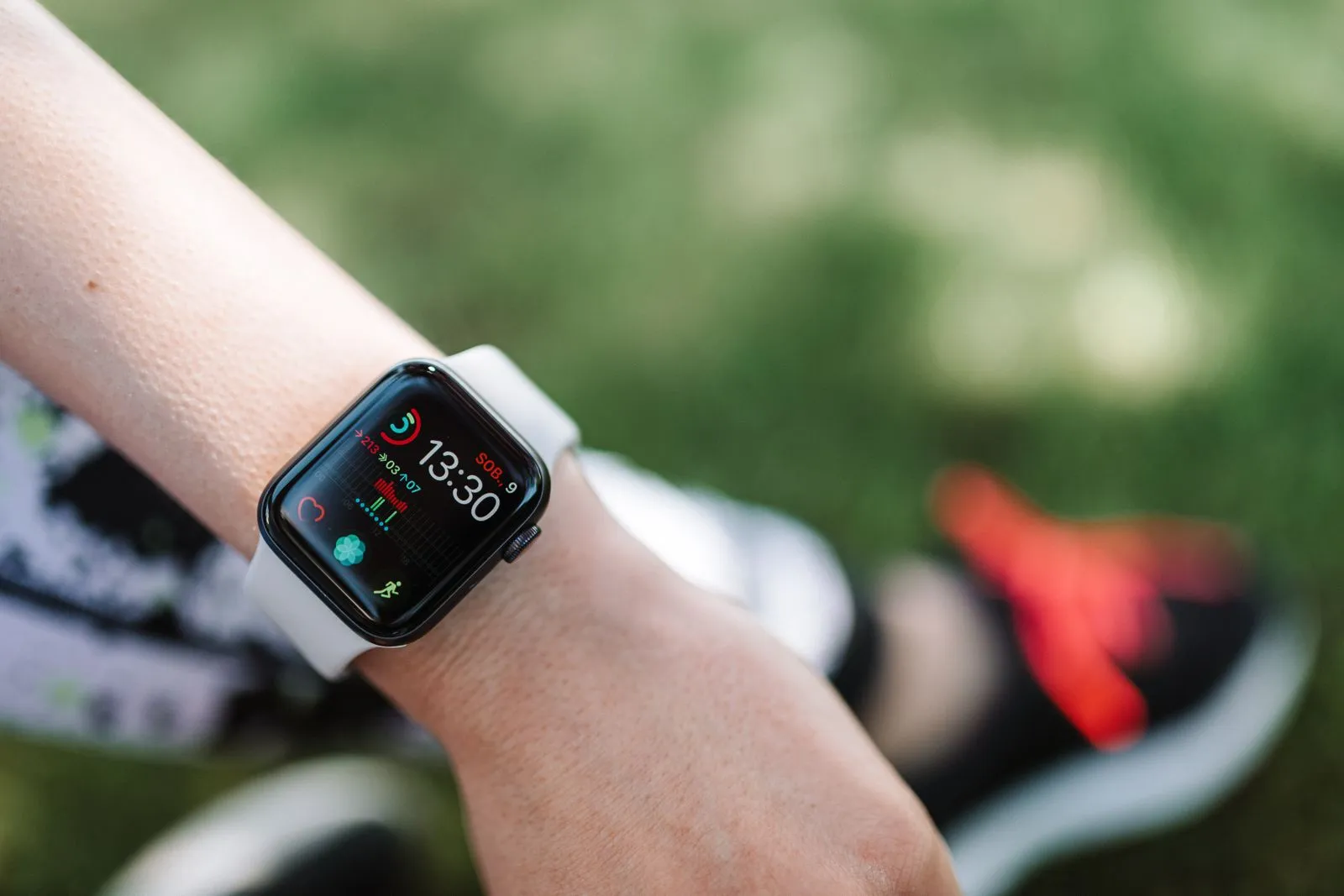 Close-up of a smartwatch on a wrist showing health metrics outdoors on a sunny day.